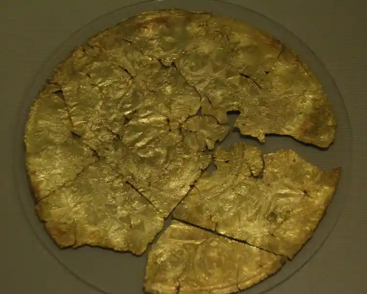 A broken gold sheet with a solar disc design
